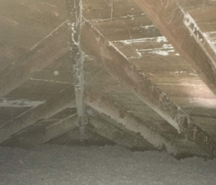 an attic with white and grey discoloration on the wood planks