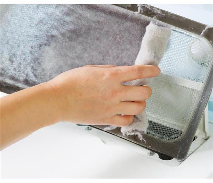 hand removing lint from lint trap