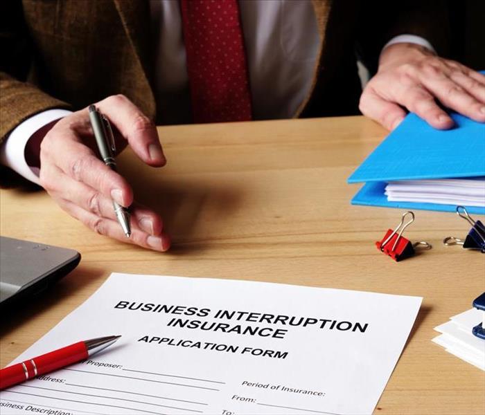 Agent offers business interruption insurance application papers.