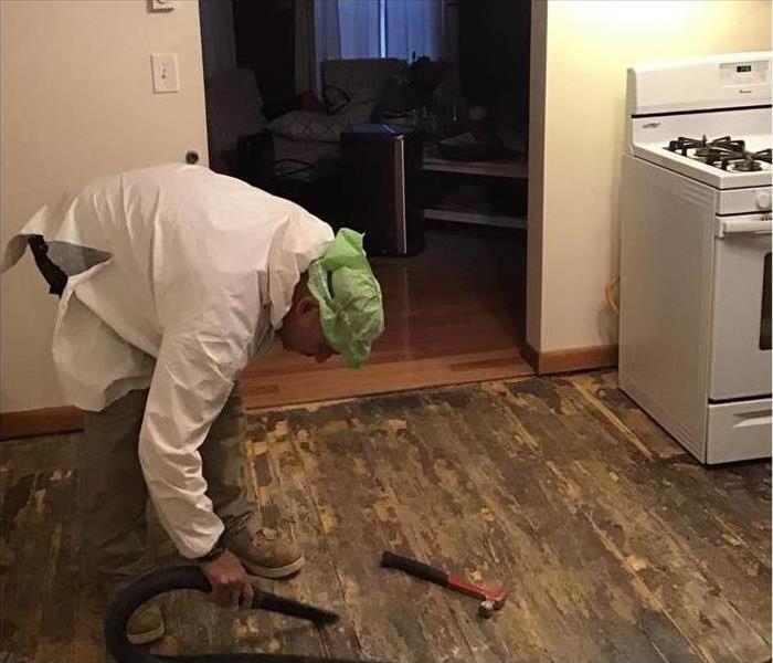 Flooring removed in a kitchen, technician using a vacuum extractor