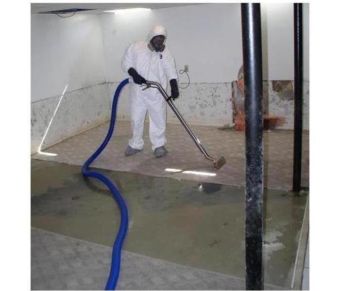 Technician wearing protective gear while removing water from a property and mold growth in property