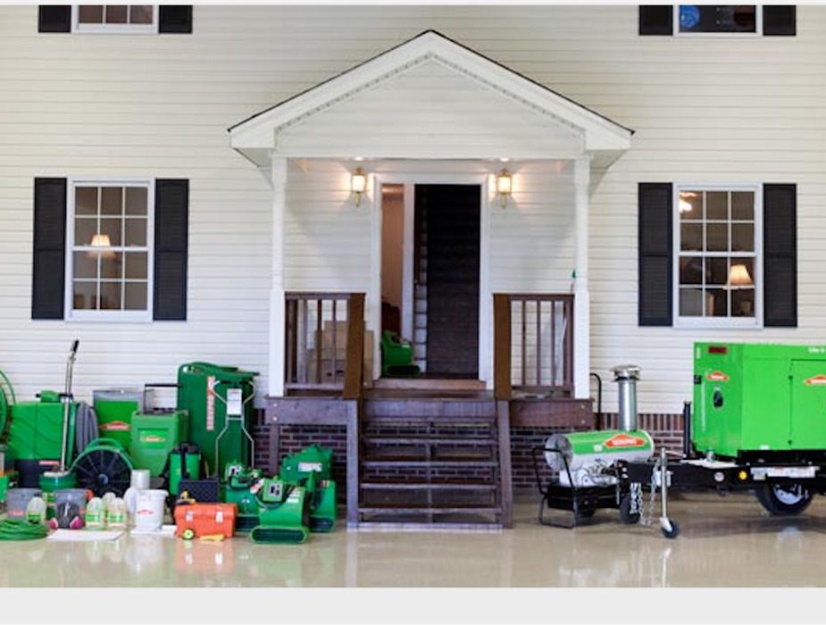 Infront of a house there is drying equipment, cleaning products, commercial generators