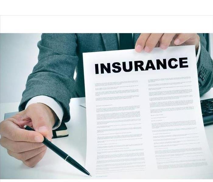 Person holding an insurance form with a pen to sign