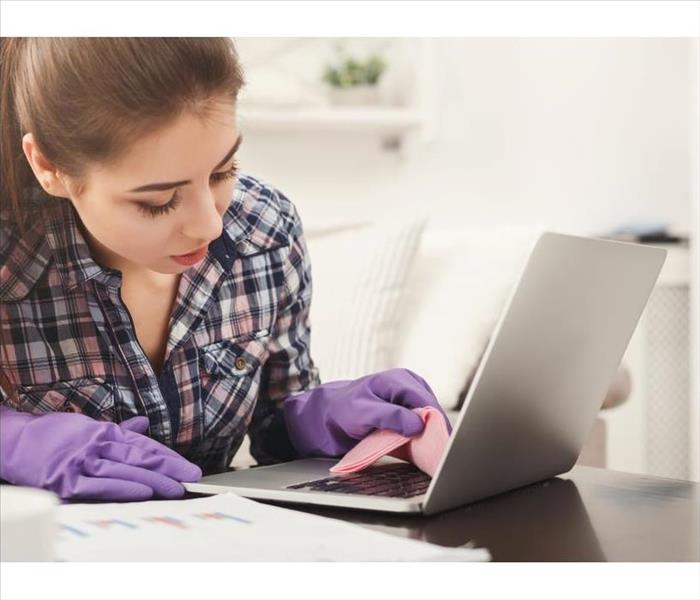 Woman cleaning laptop keyboard.
